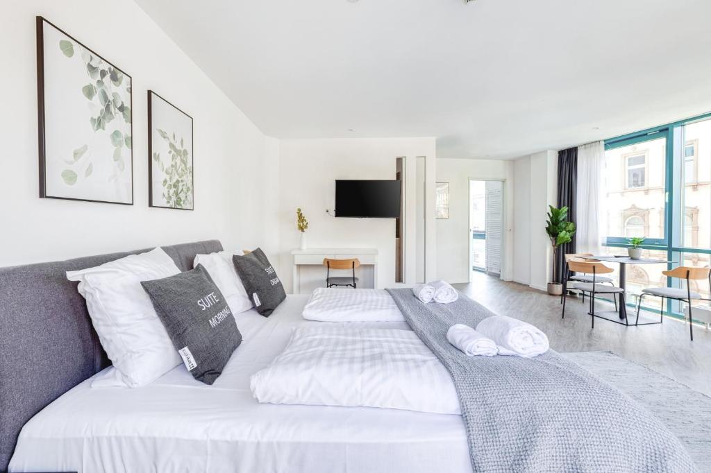 a white bedroom with a large white bed with pillows at limehome Köln Friesenplatz - Digital Access in Cologne