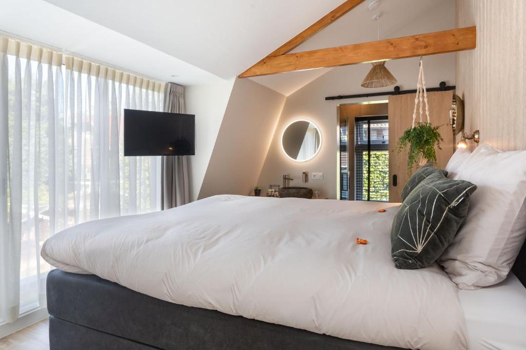 een slaapkamer met een groot bed met witte lakens en kussens bij B&B De Mansarde in Apeldoorn