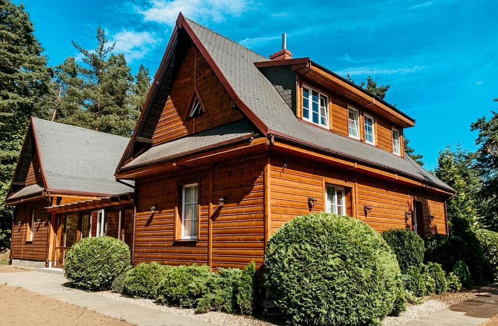 une grande maison en bois avec un toit noir dans l'établissement Leśny Zakątek Borkowo, à Borkowo