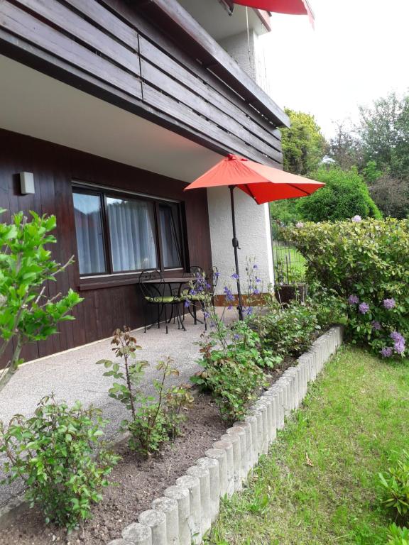 a patio with a red umbrella next to a house at Ferien am Wald in Baiersbronn