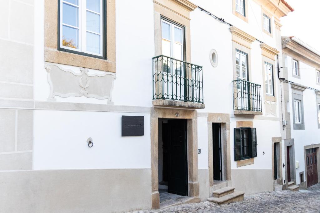 un edificio bianco con porta nera e balcone di A BURGUESA - GUESTHOUSE a Castelo de Vide