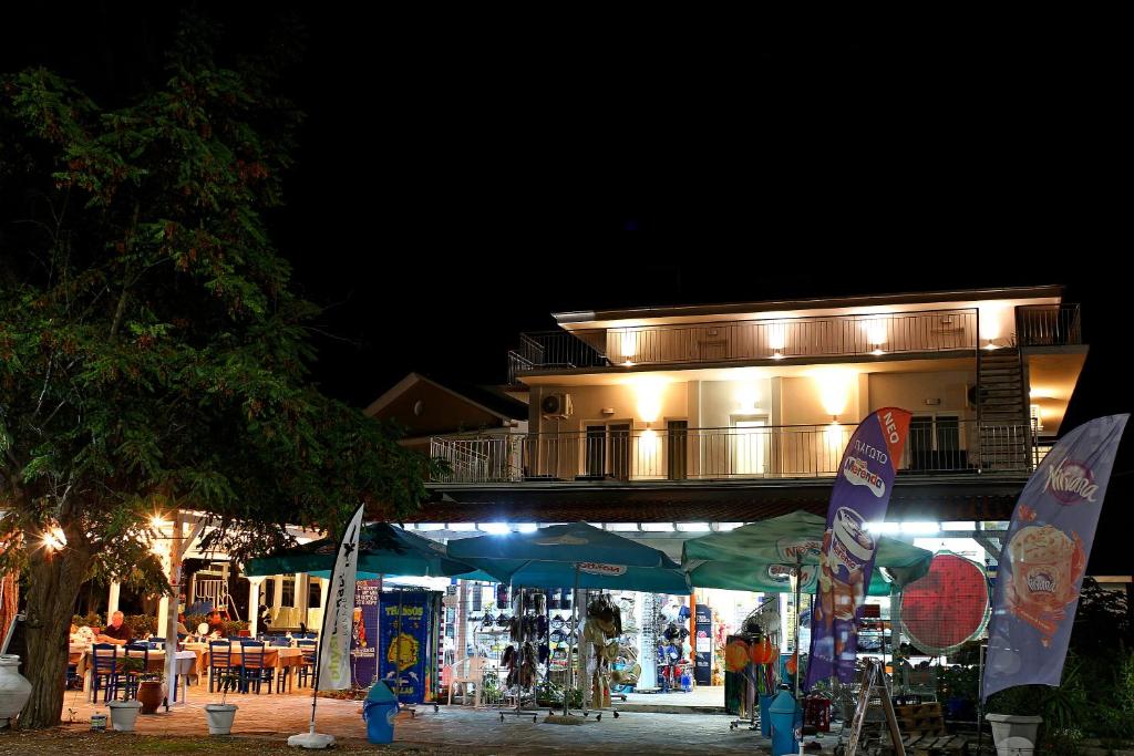 um edifício à noite com um mercado em frente em Oneiro Zois em Prinos