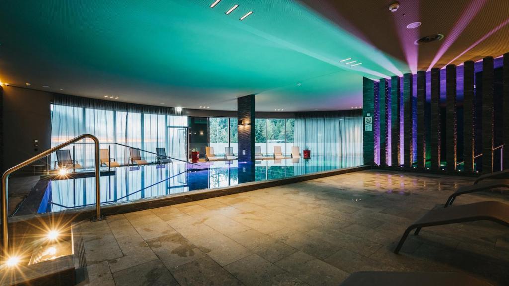 una piscina coperta in un edificio con luci blu di Peaks Place Apartments & SPA a Laax