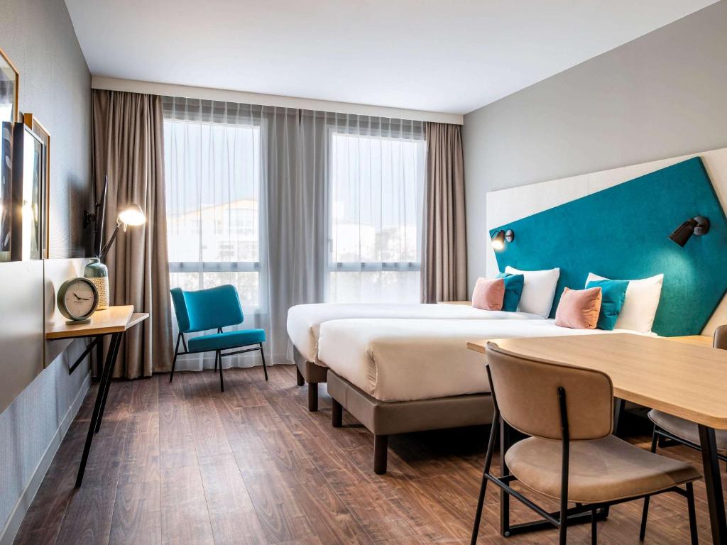 um quarto de hotel com uma cama grande e uma secretária em Aparthotel Adagio Paris Suresnes Longchamp em Suresnes