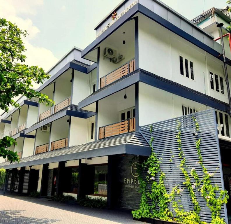 - un bâtiment blanc avec des balcons bleus dans une rue dans l'établissement Emperor-Hotel Rachana Continental Pvt Ltd, à Kizhake Chālakudi