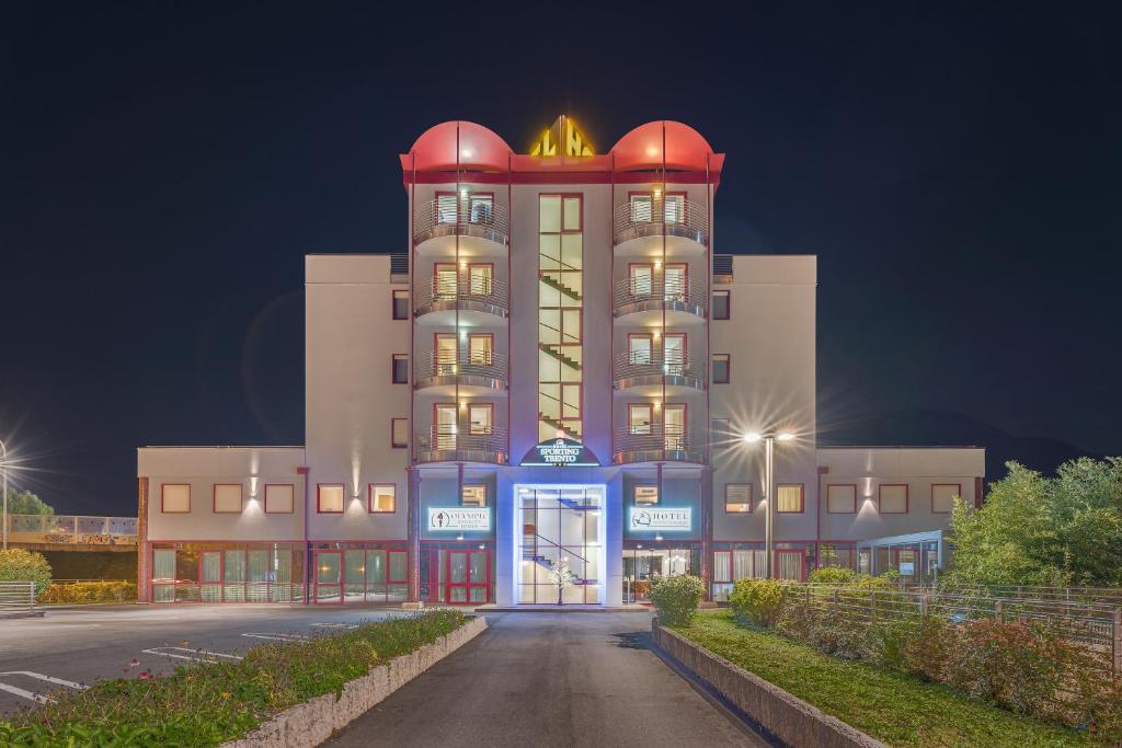 een groot gebouw met 's nachts een toren bij Hotel Sporting Trento in Trento