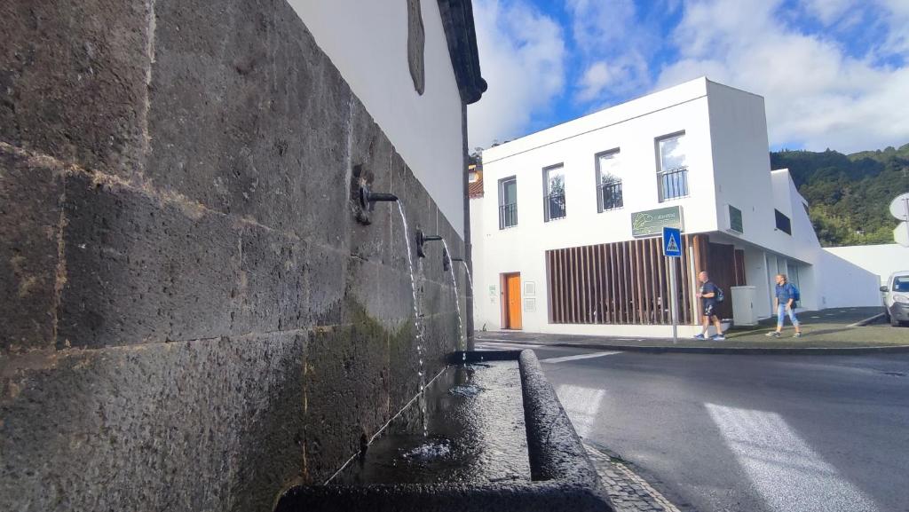 una pared de ladrillo junto a una calle con un edificio en Atlantic 3 Bicas - Furnas, en Furnas