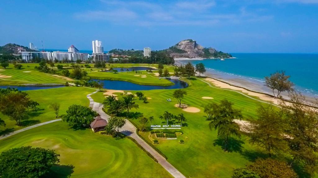 Seapine Beach Golf and Resort Hua Hin في هوا هين: اطلالة جوية على ملعب قولف مع المحيط