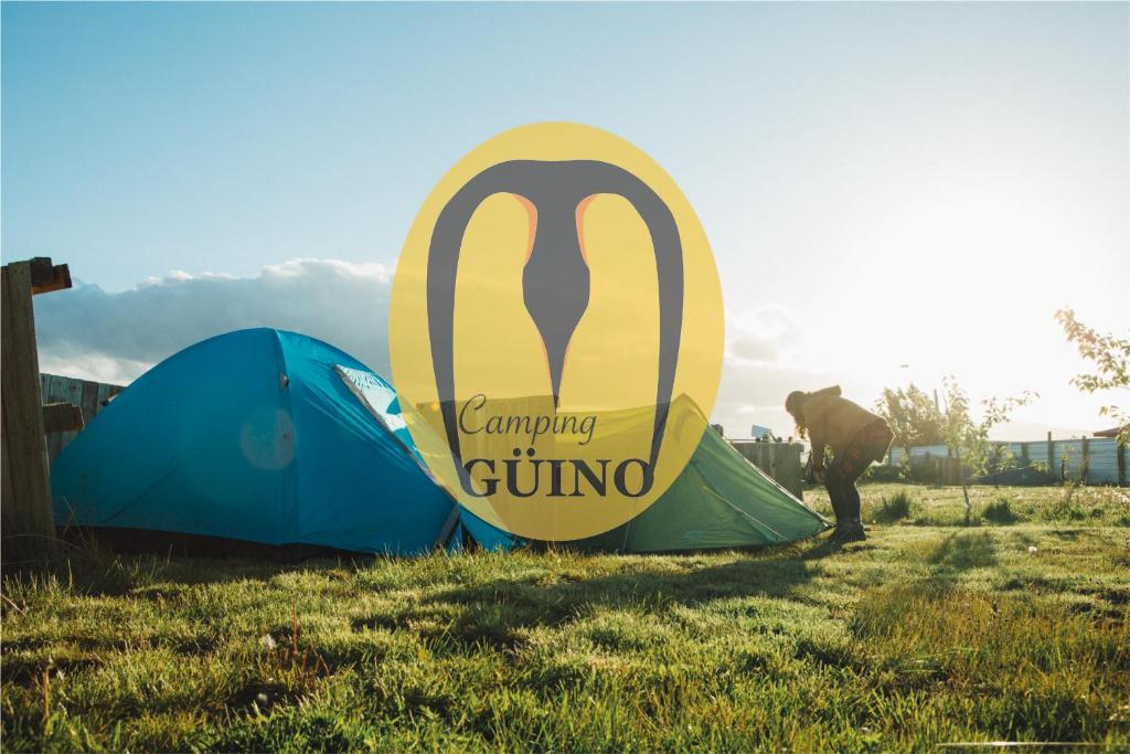 a man standing next to two tents in a field at Camping Güino in Puerto Natales