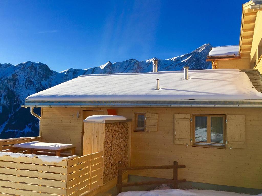 uma casa com um telhado de neve com montanhas ao fundo em Holiday Home Maiensäss Superior by Interhome em Urmein