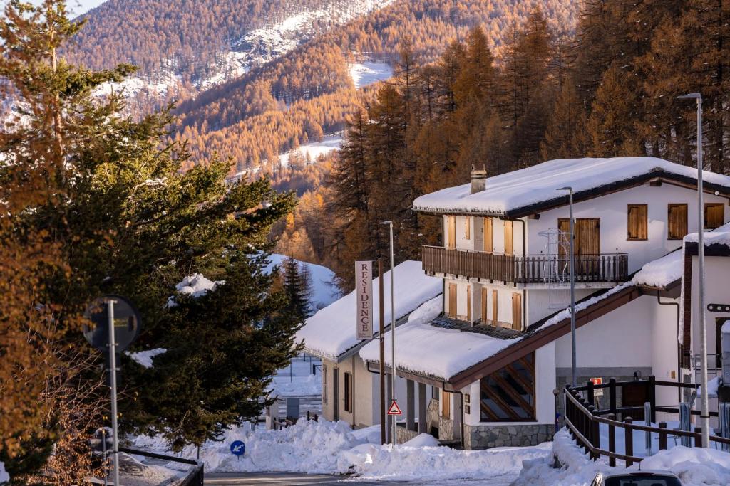 um edifício coberto de neve com uma montanha ao fundo em Residence Nube D'Argento em Sestriere