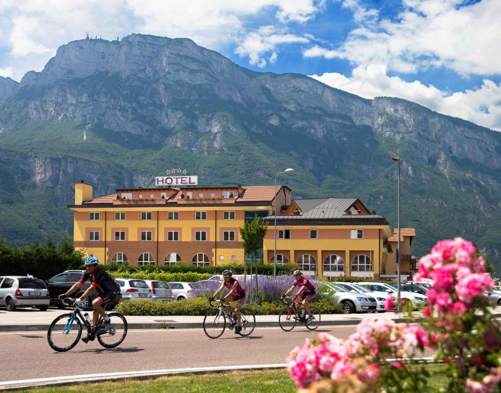 3 personnes empruntant des vélos sur une route devant un bâtiment dans l'établissement Sartori's Hotel, à Trente