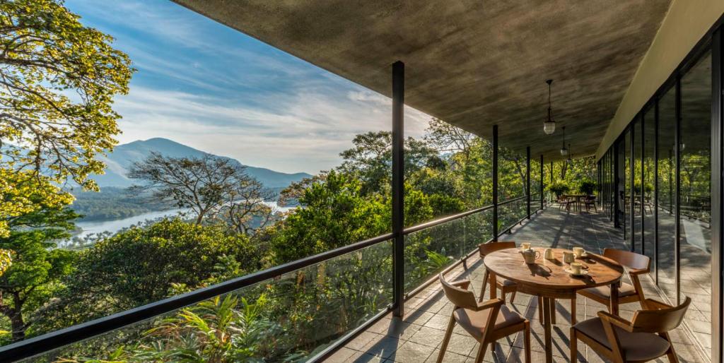 Zimmer mit einem Tisch und Stühlen auf einem Balkon in der Unterkunft Elakai in Munnar