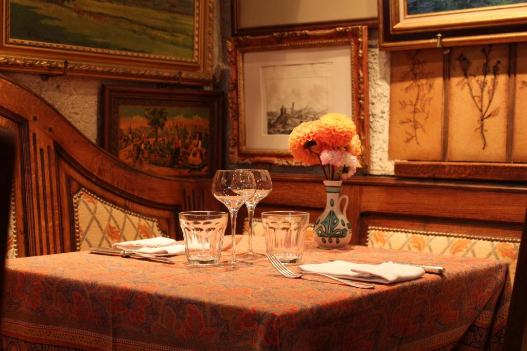 a table with wine glasses and a vase with flowers on it at Hôtel Restaurant Le Schlossberg in Zellenberg