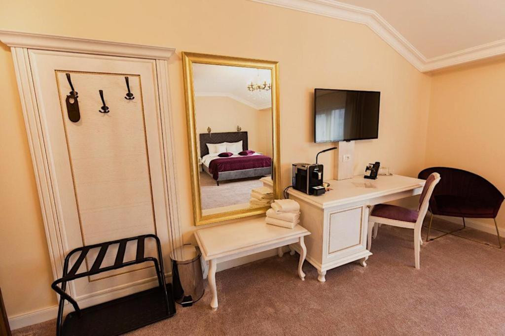 Cette chambre comprend un bureau et un lit avec un miroir. dans l'établissement 4Cardinal's Hotel Boutique, à Braşov