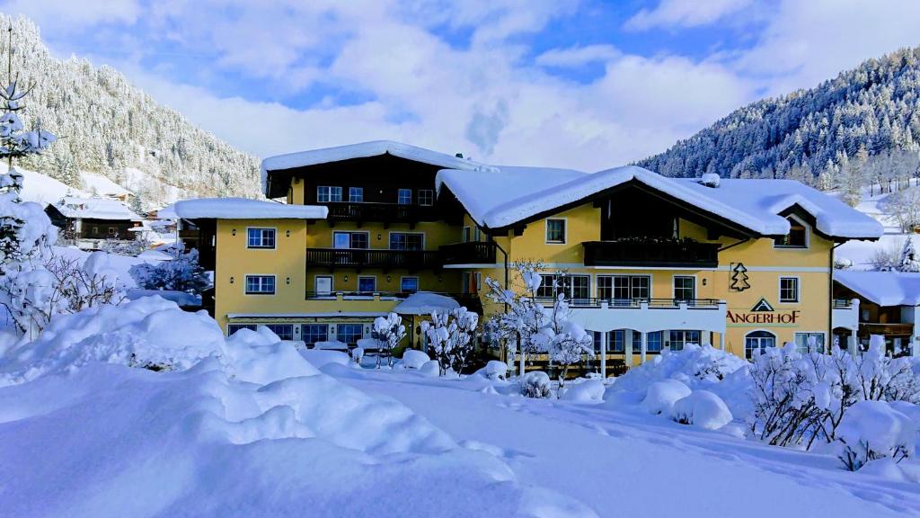 un gran edificio amarillo cubierto de nieve en Jugendhotel Angerhof, en Oberau