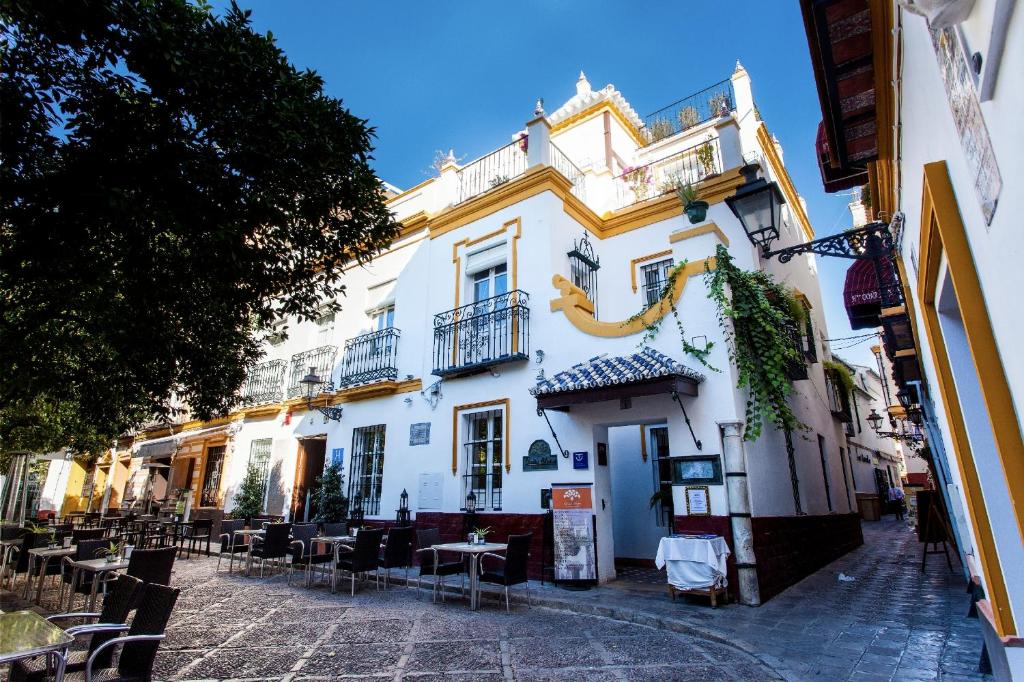 ein weißes Gebäude mit Tischen und Stühlen auf einer Straße in der Unterkunft Hotel Boutique Elvira Plaza in Sevilla