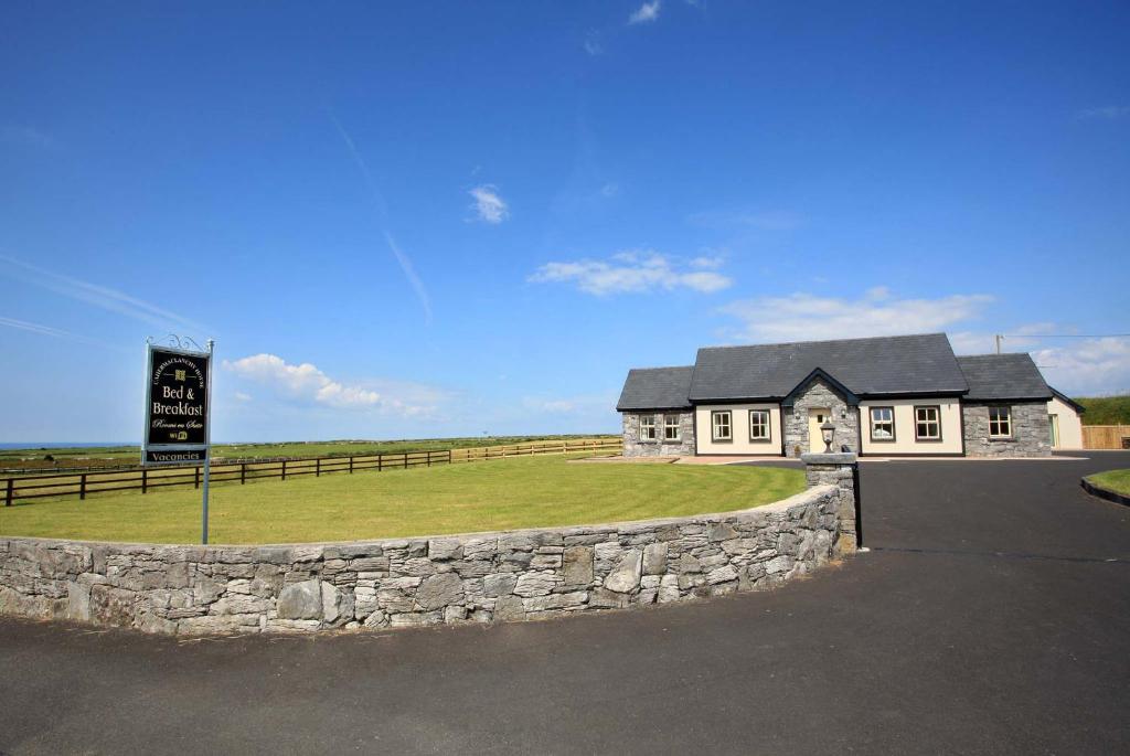 una casa bianca con un muro di pietra e un cartello di Cahermaclanchy House B&B a Doolin