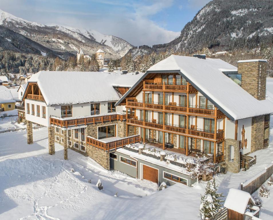 een huis in de sneeuw met bergen op de achtergrond bij Hotel Haus Lungau in Mauterndorf