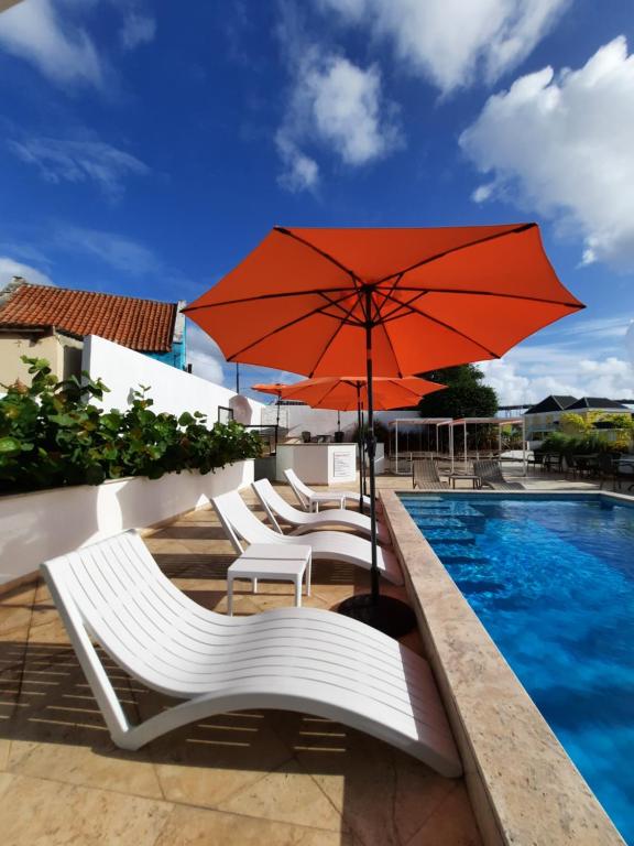 - un groupe de chaises et un parasol à côté de la piscine dans l'établissement The Freedom Hotel, à Willemstad