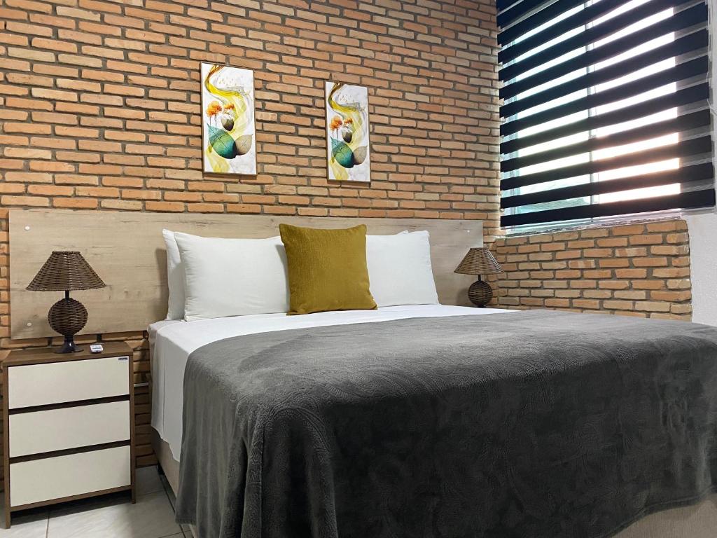 um quarto com uma cama grande e uma parede de tijolos em B & A Suites Inn Flats - Apart Flat Stratus em Anápolis