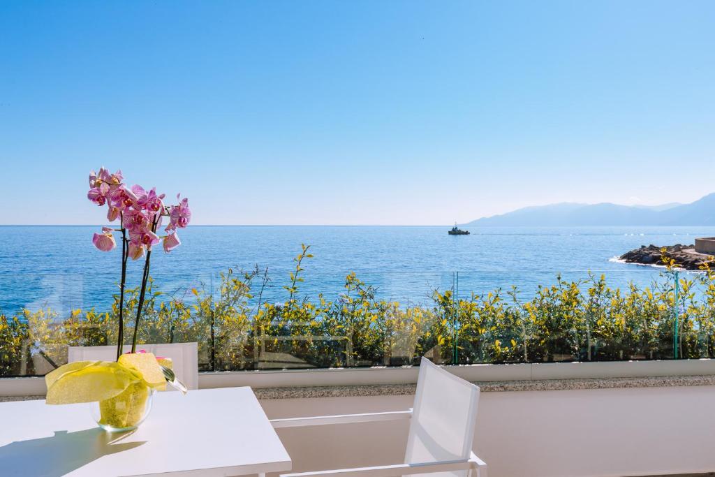 un tavolo con un vaso di fiori in cima all'oceano di Hotel Caramare a Cala Gonone