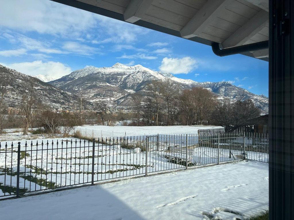 uma vista para uma montanha coberta de neve através de uma cerca em Villa Kate alloggio ad uso turistico VDA Gressan 0161 em Aosta