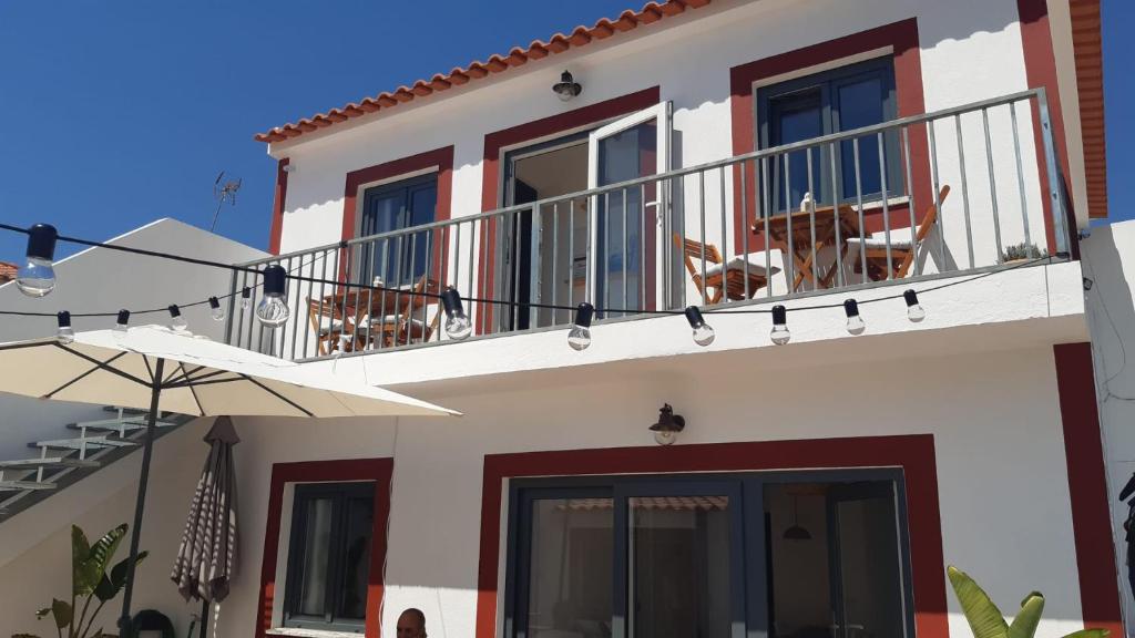 una casa con balcone e sedie di Cantinho de Milfontes 1 a Vila Nova de Milfontes