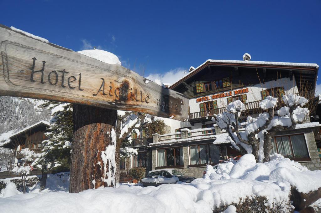 ein Schild im Schnee vor einem Gebäude in der Unterkunft Hotel Aiguille Noire in Courmayeur