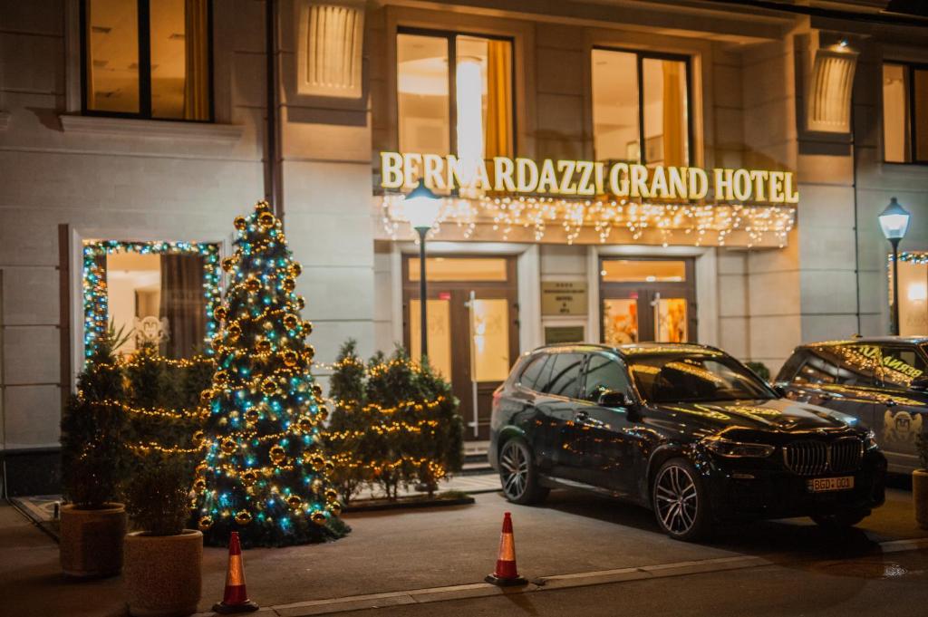 une voiture garée devant un immeuble avec un arbre de Noël dans l'établissement Bernardazzi Grand Hotel, à Chişinău