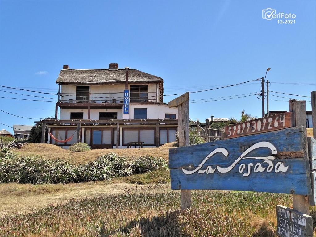 ein Schild vor einem Gebäude mit einem Haus in der Unterkunft La Posada in Punta Del Diablo