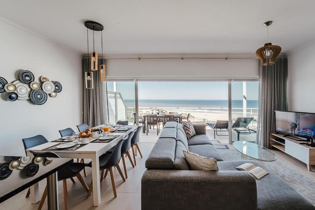 ein Wohnzimmer mit Sofa und ein Esszimmer mit Strand in der Unterkunft Beachfront Atlantic Sunset A07 in Óbidos