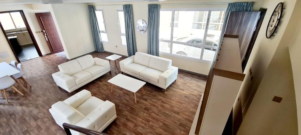 uma sala de estar com duas cadeiras brancas e uma mesa em HAVANA HOLIDAY HOMES MIRDIF no Dubai