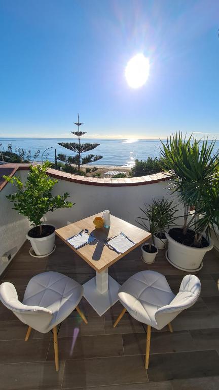 een tafel en stoelen op een balkon met uitzicht op de oceaan bij Pantanello Rooms Avola in Avola