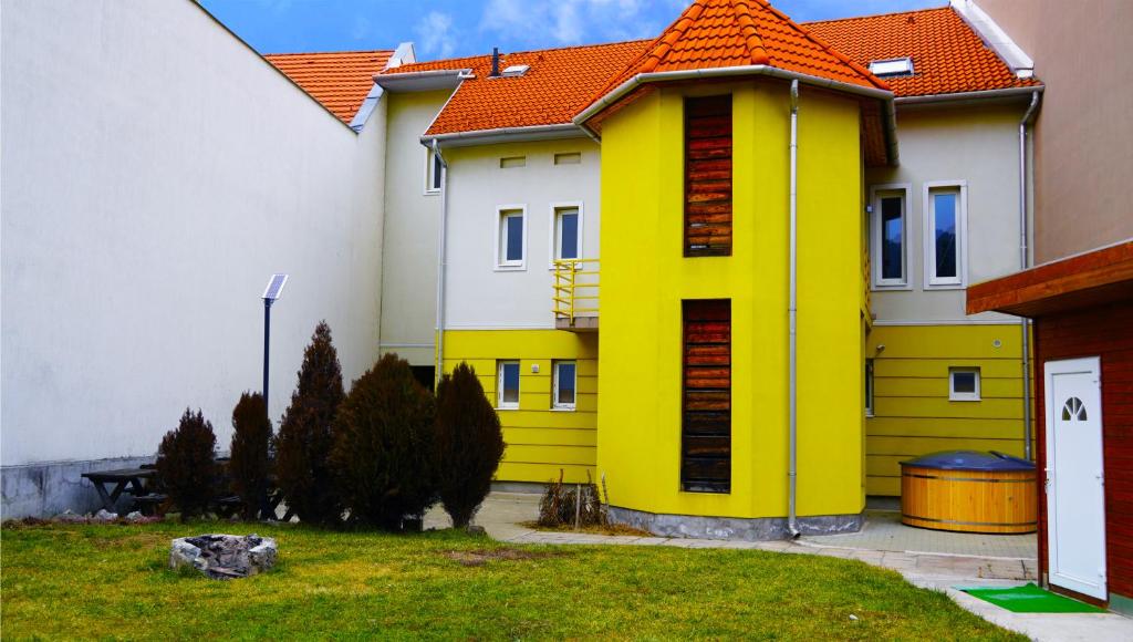 ein gelbes Haus mit orangefarbenem Dach im Hof in der Unterkunft Pajkos Póni Vendégház in Miskolc