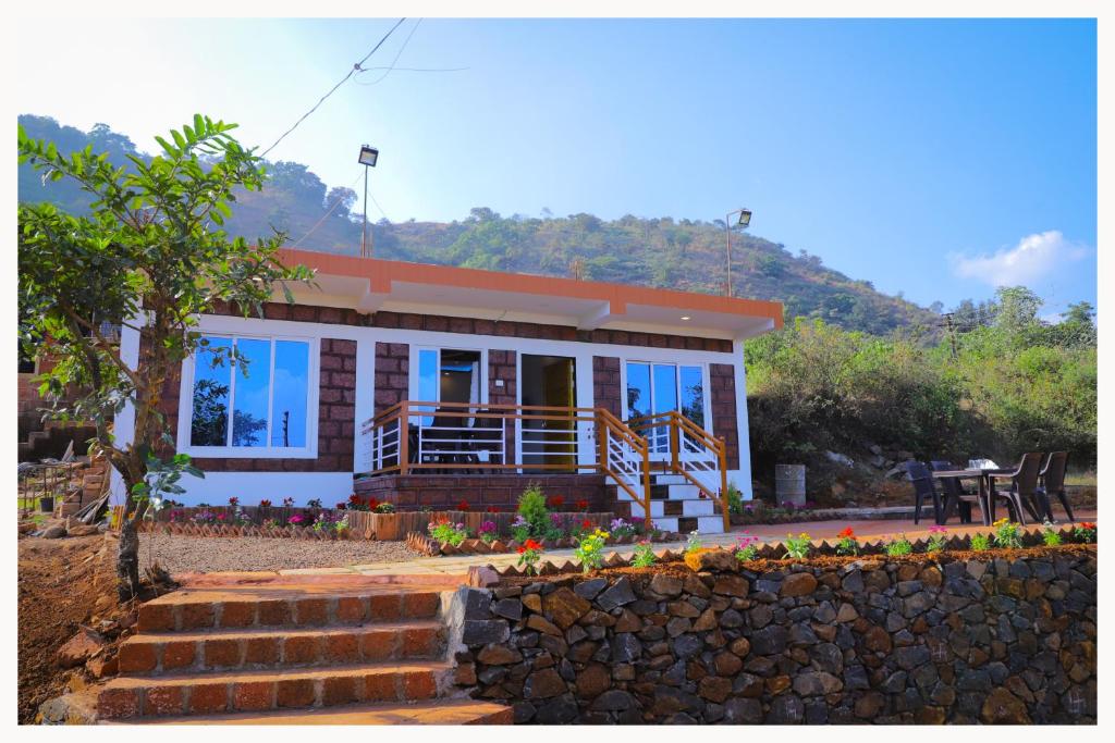 uma casa com uma parede de pedra em frente em Sai Siddhigiri Villa em Mahabaleshwar