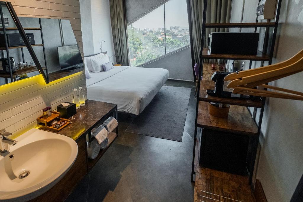 Cette chambre comprend un lit, un lavabo et une fenêtre. dans l'établissement Janevalla Bandung, à Bandung