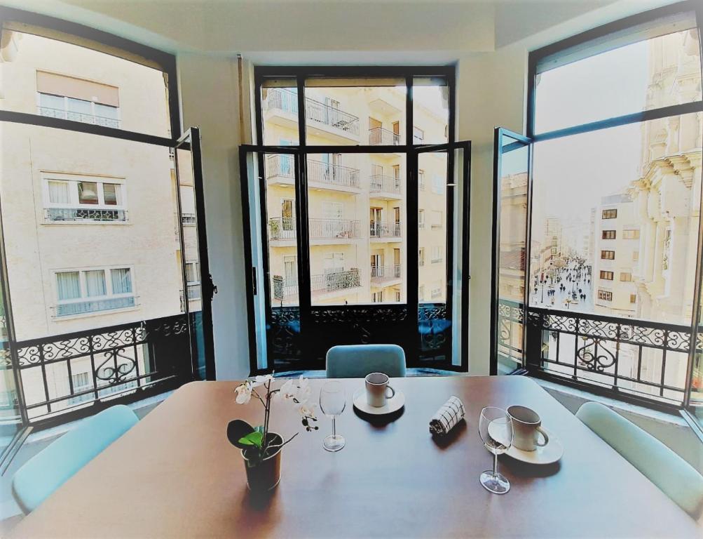 ein Esszimmer mit einem Tisch und großen Fenstern in der Unterkunft Apartamentos Vega by gaiarooms in Salamanca