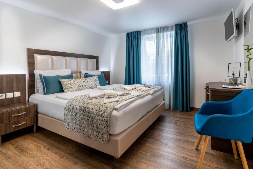 - une chambre avec un lit et une chaise bleue dans l'établissement Hotel Myrsini, à Kirchentellinsfurt