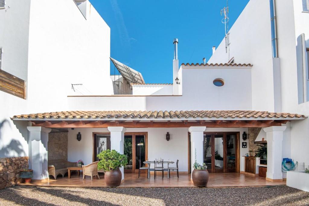 Cette maison blanche dispose d'une terrasse avec une table et des chaises. dans l'établissement Ses Àmfores, à Ciutadella