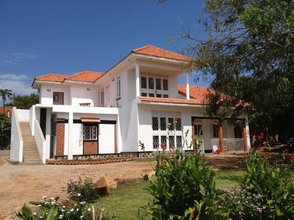 uma casa branca com um telhado vermelho em Alison & Dave's Guesthouse em Entebbe