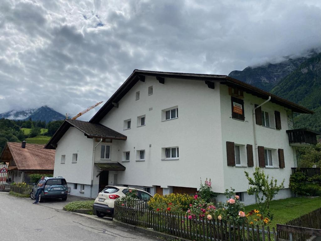 a white house with cars parked in front of it at Spring Inn Apartments in Meiringen