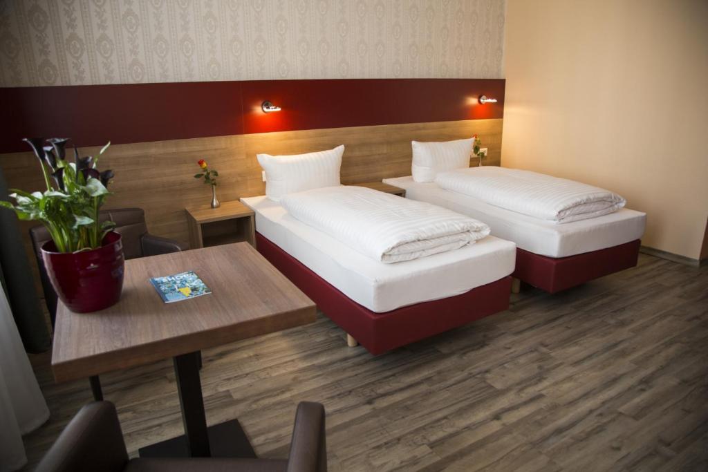 a hotel room with two beds and a table at Hotel City Panorama in Hannover