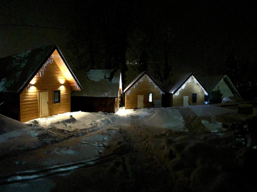 uma fila de casas iluminadas na neve à noite em Poncyljuszówka em Szczyrk