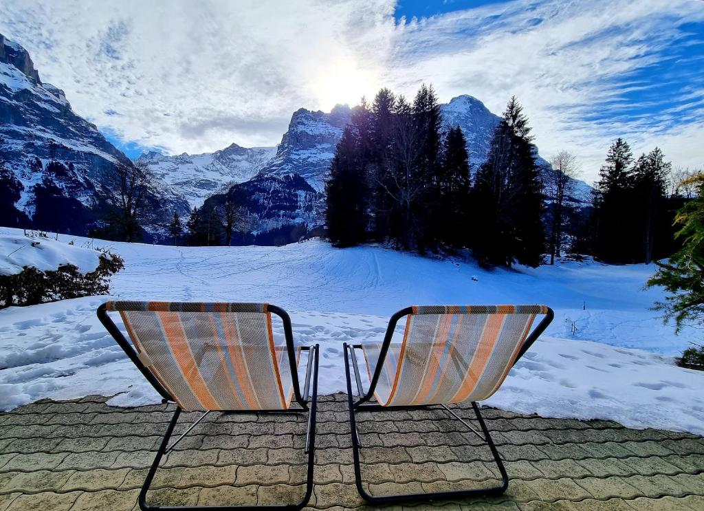 dwa krzesła siedzące przed pokrytą śniegiem górą w obiekcie MOM - Alpine Boutique Apartments, Grindelwald gletscher, Eiger View Terrace Studio w mieście Grindelwald