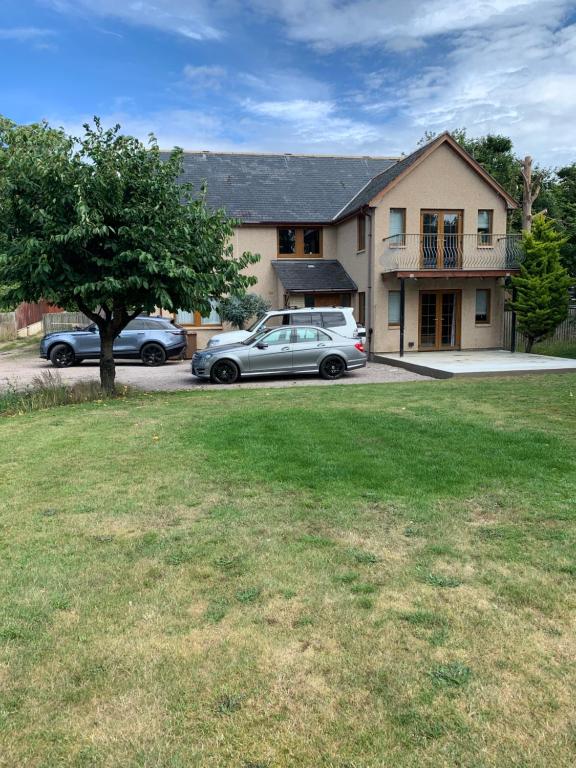 una casa con dos coches aparcados en un patio en Tanglewood Lodge, en Lossiemouth