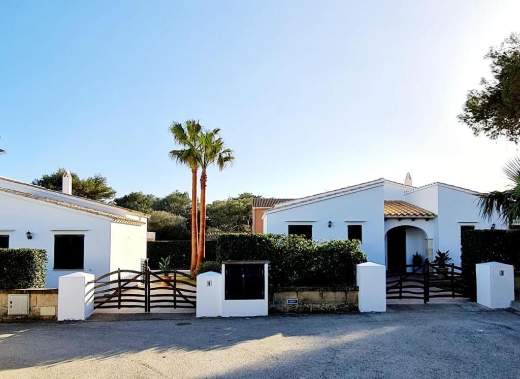 une maison blanche avec un portail et un palmier dans l'établissement Villas El Pinar, à Cala en Blanes