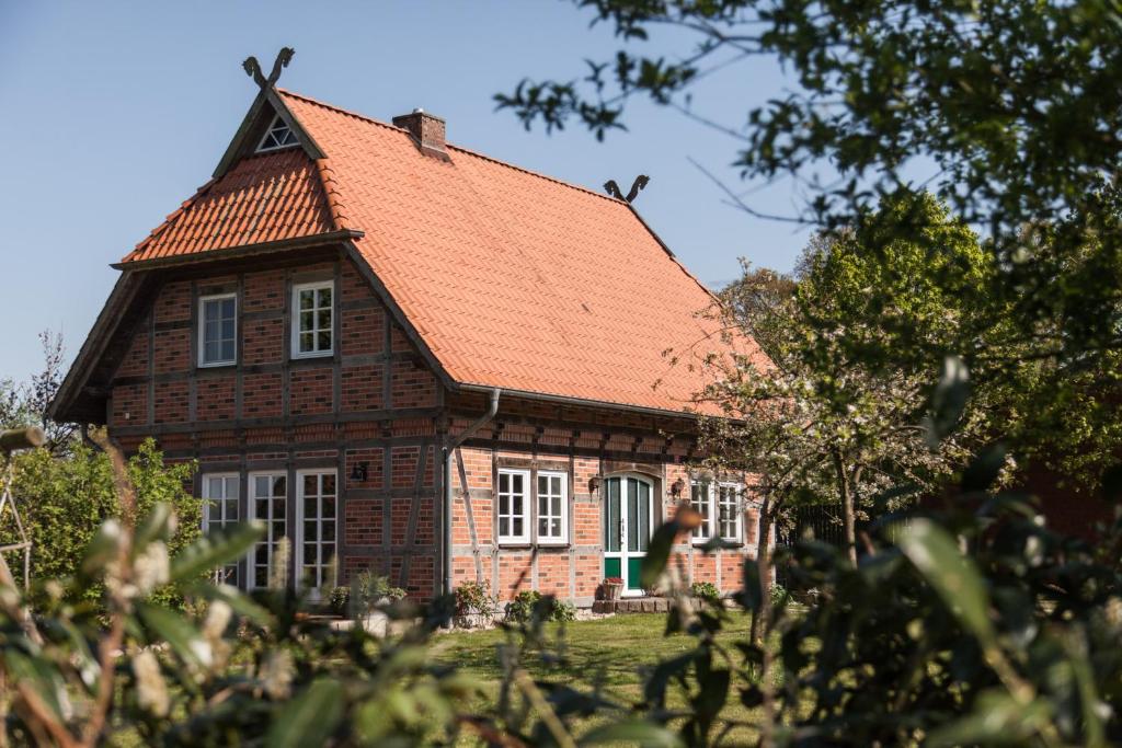 Fachwerk-Ferienhaus, Ruhe auf dem Land, Haustiere willkommen, Leihfahrräder, 24-7 check in في Kirchlinteln: منزل من الطوب وسقف برتقال