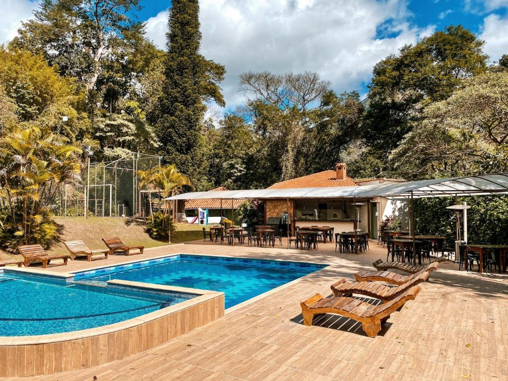 une piscine avec des chaises et des tables ainsi qu'une maison dans l'établissement Hotel Vila Bavária Petrópolis, à Petrópolis