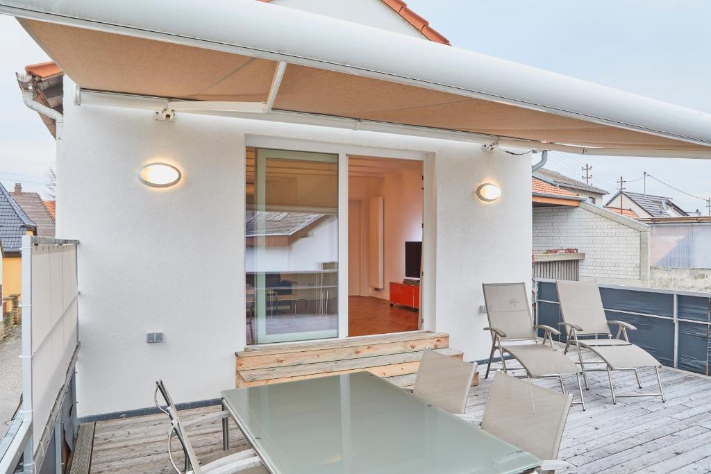 un patio con tavolo in vetro e sedie sul balcone. di Klimatisierte Wohnung mit großer Terrasse a Deidesheim